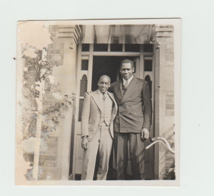 An image of a photograph showing Akiki Nyabongo in a light suit standing next to Paul Robeson wearing a dark suit