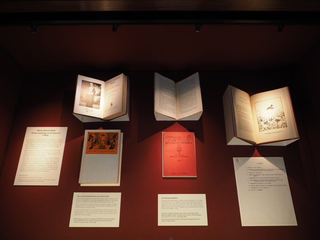 Image shows a display case containing 3 books mounted open, two books closed and four text panels.