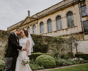 Bride and groom kissing in the Fellows' Garden with the Library building in the background