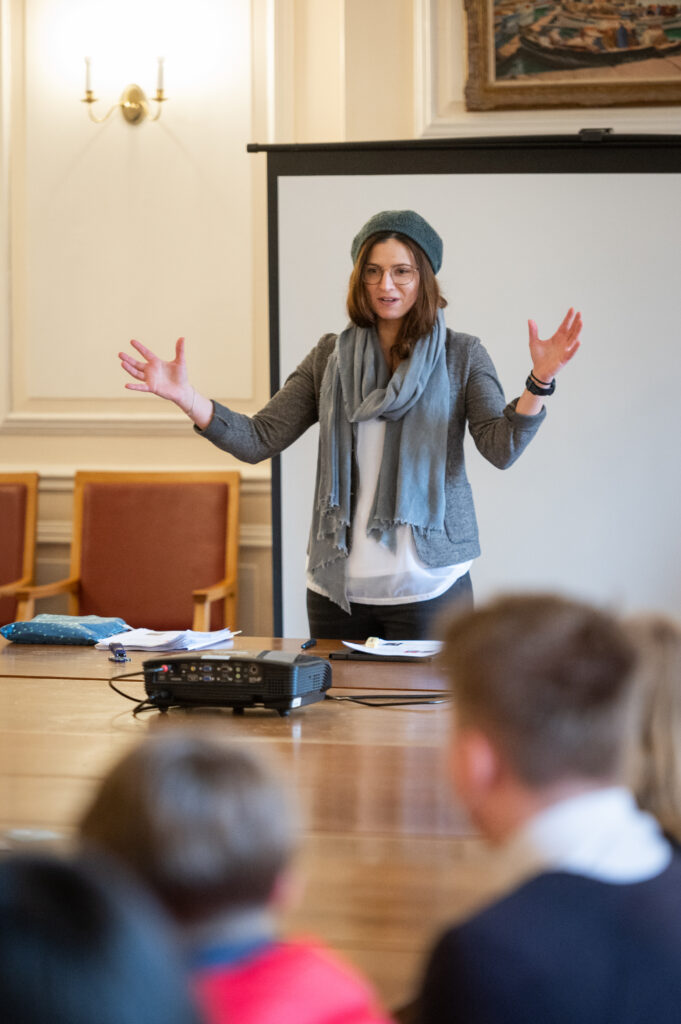 tutor presenting to pupils with open arms
