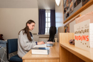 undergraduate bedroom with student seated at her desk