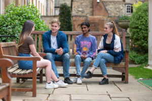 group of four students chatting on a bench