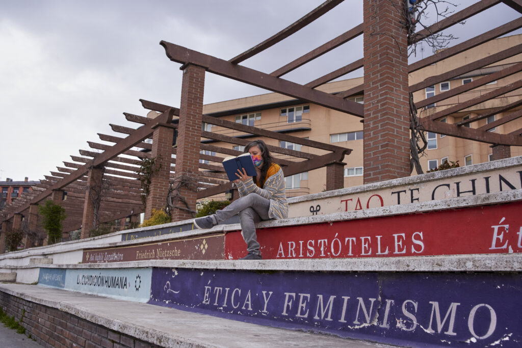 woman sitting reading on steps that look like books