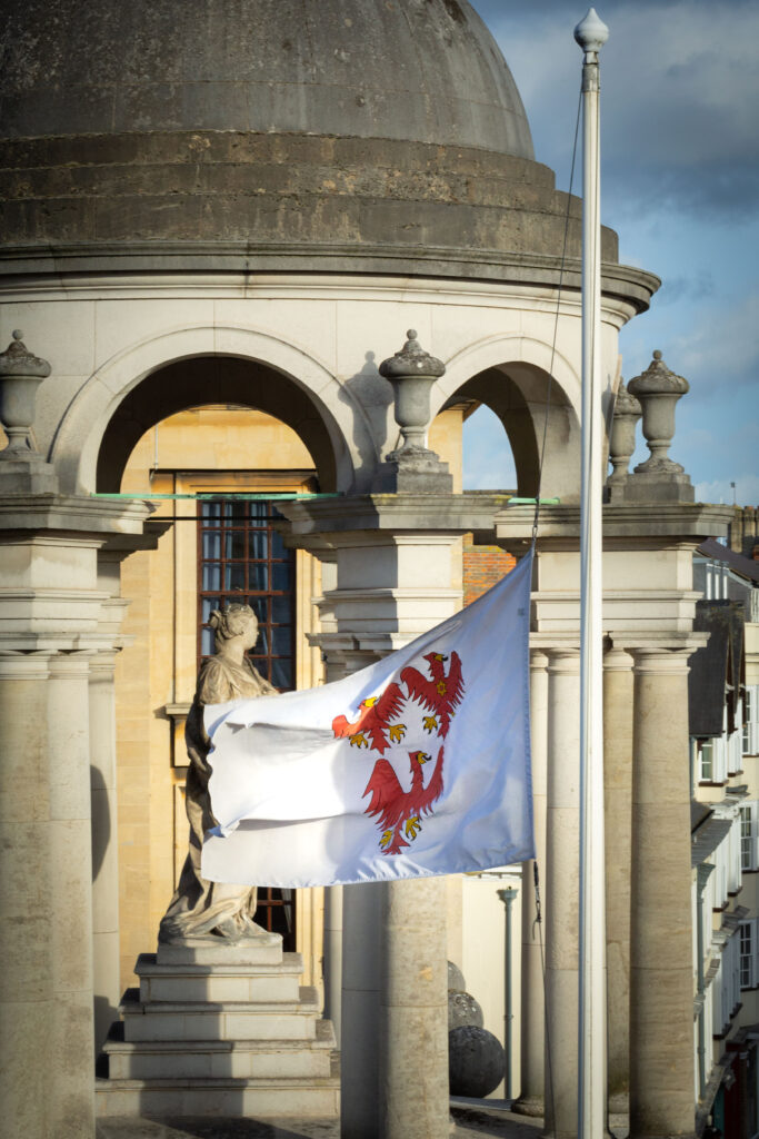 College flag flying in front of the cupola