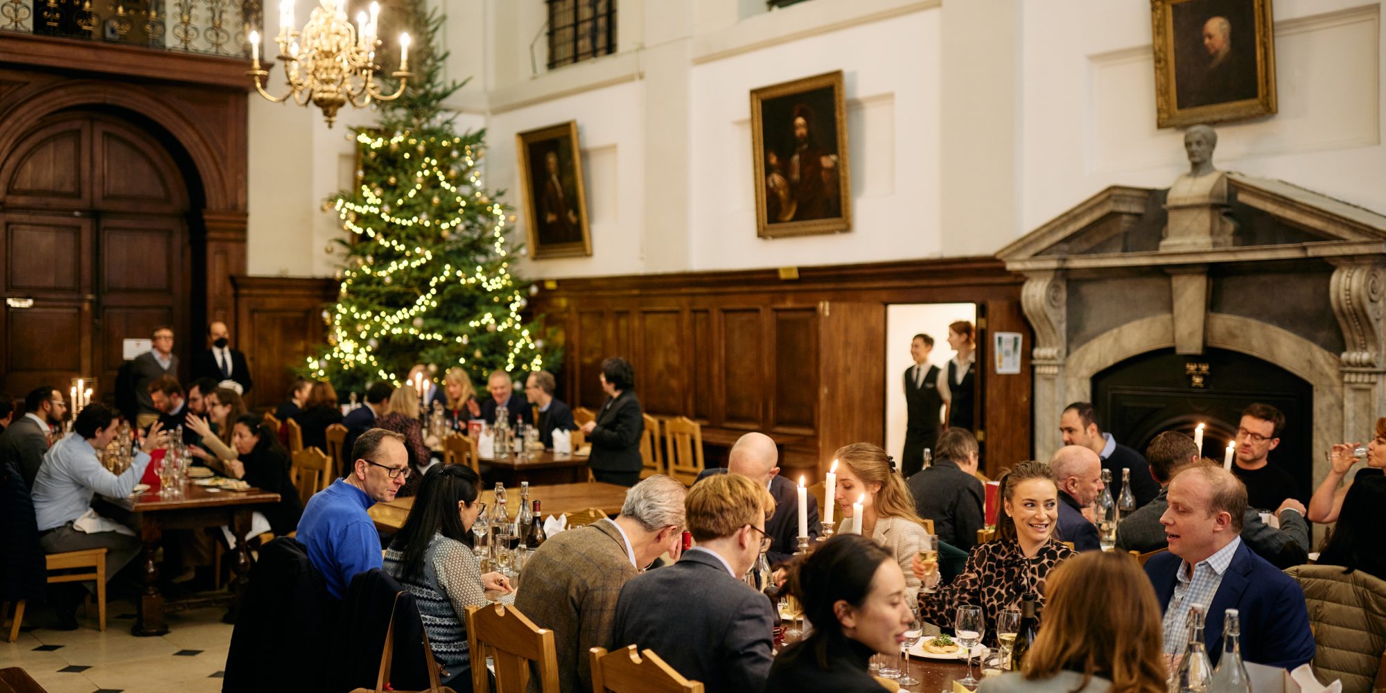 People dining in Hall with Christmas tree in the background
