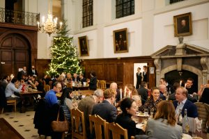 People dining in Hall with Christmas tree in the background