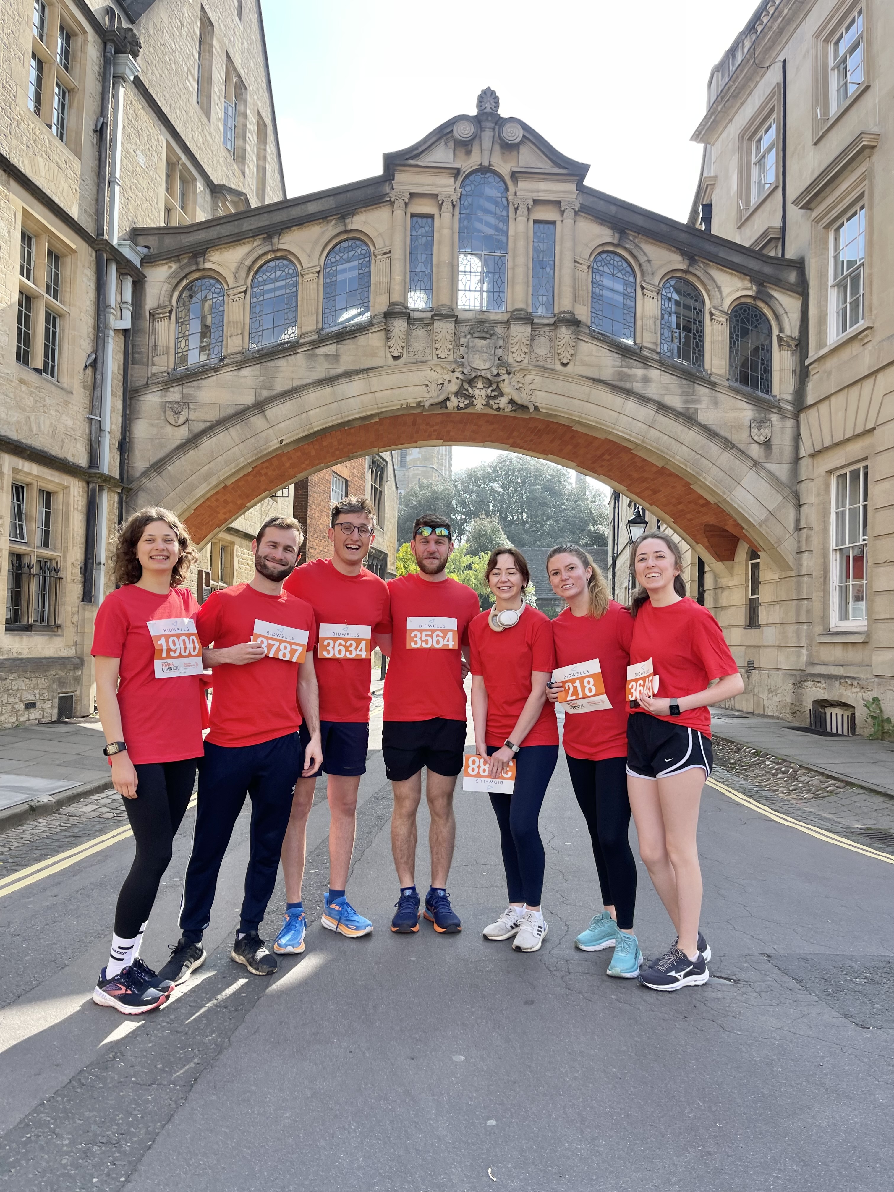 A group of students in red t-shirts standing underneath the Bridge of Sighs in Oxford on the day of the Town and Gown race