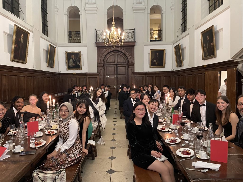 The dining Hall filled with people sitting along the benches at the Confluence formal dinner