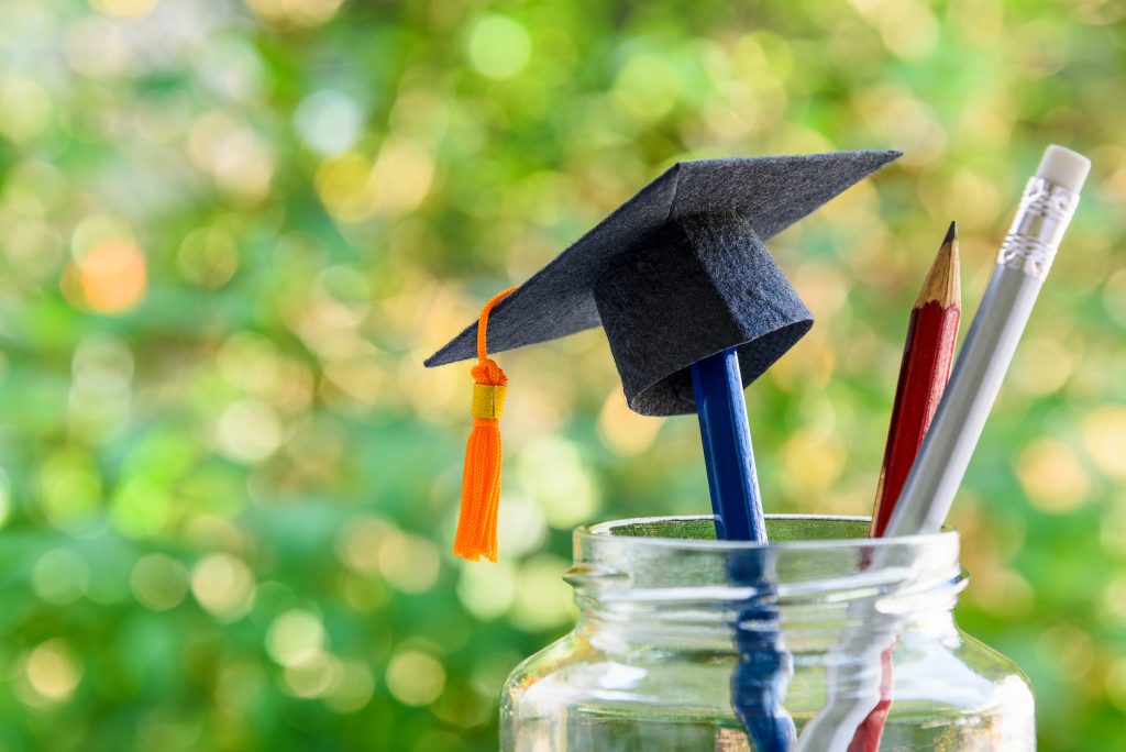 Black graduation cap and a pencil in a bottle.