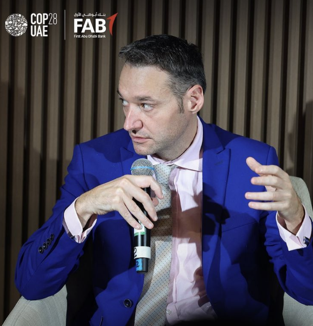 Prof Ludo Phalippou at COP28 wearing a blue suit jacket and holding a microphone