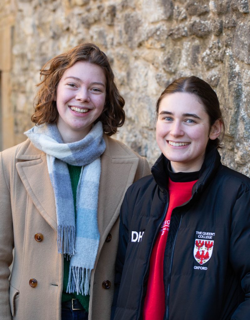 Bryony and Dani pictured together against the stone walls in the Fellows' Garden