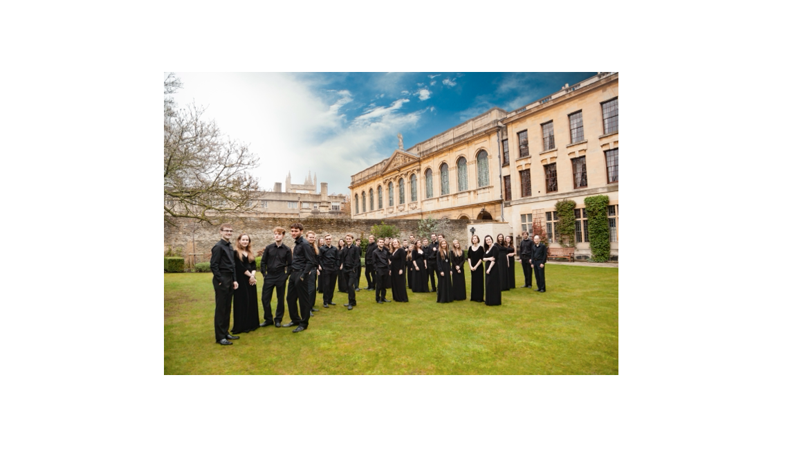 The Choir of The Queen's College standing in the Fellows' Garden with the library in the background