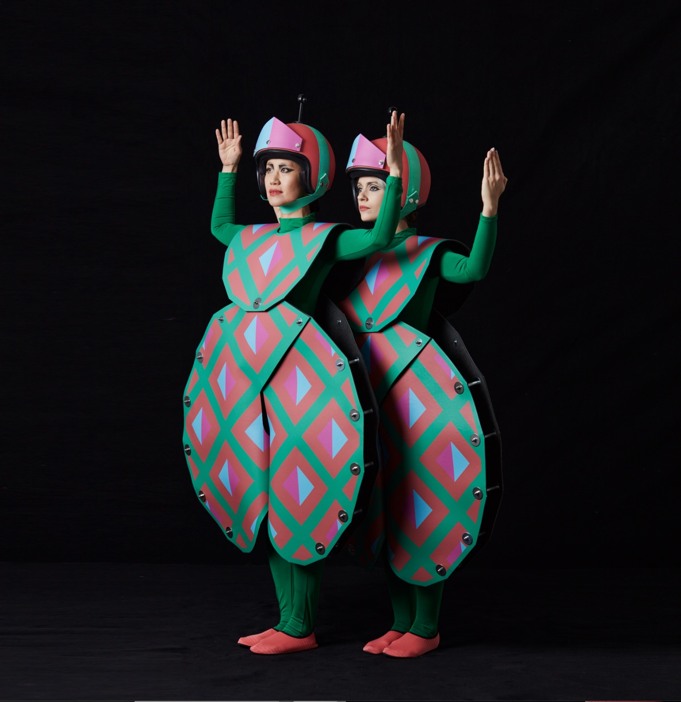 an example of Di Mainstone's costume work on a black background showing two women dressed in a green and pink costume
