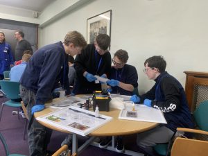 student outreach activities taking place with students around tables in a lecture room at Queen's