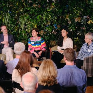 a photo of the panellists with foliage behind and the back of audience members in the foreground