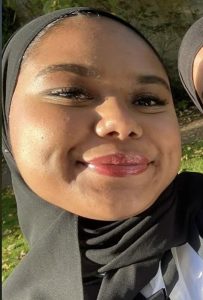 Profile photo of Alina smiling and wearing Sub Fusc (white shirt and black ribbon) for Matriculation Day