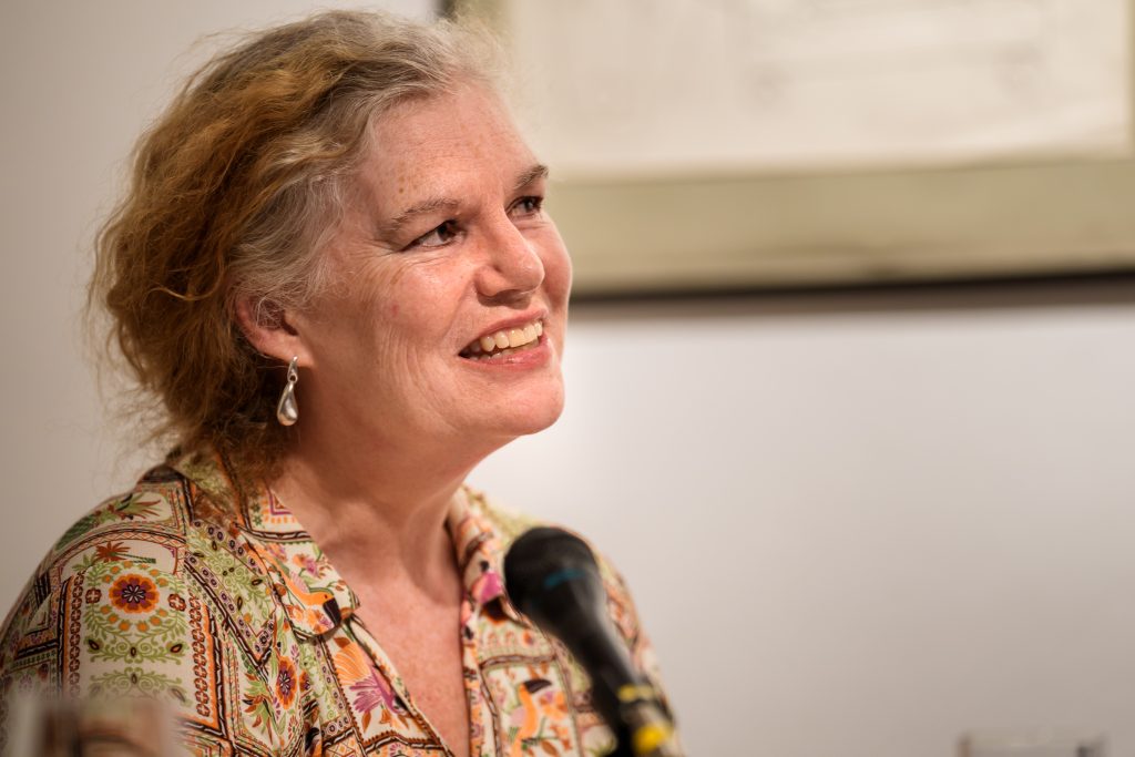 Professor Leeder profile photo. She stands at a lectern.