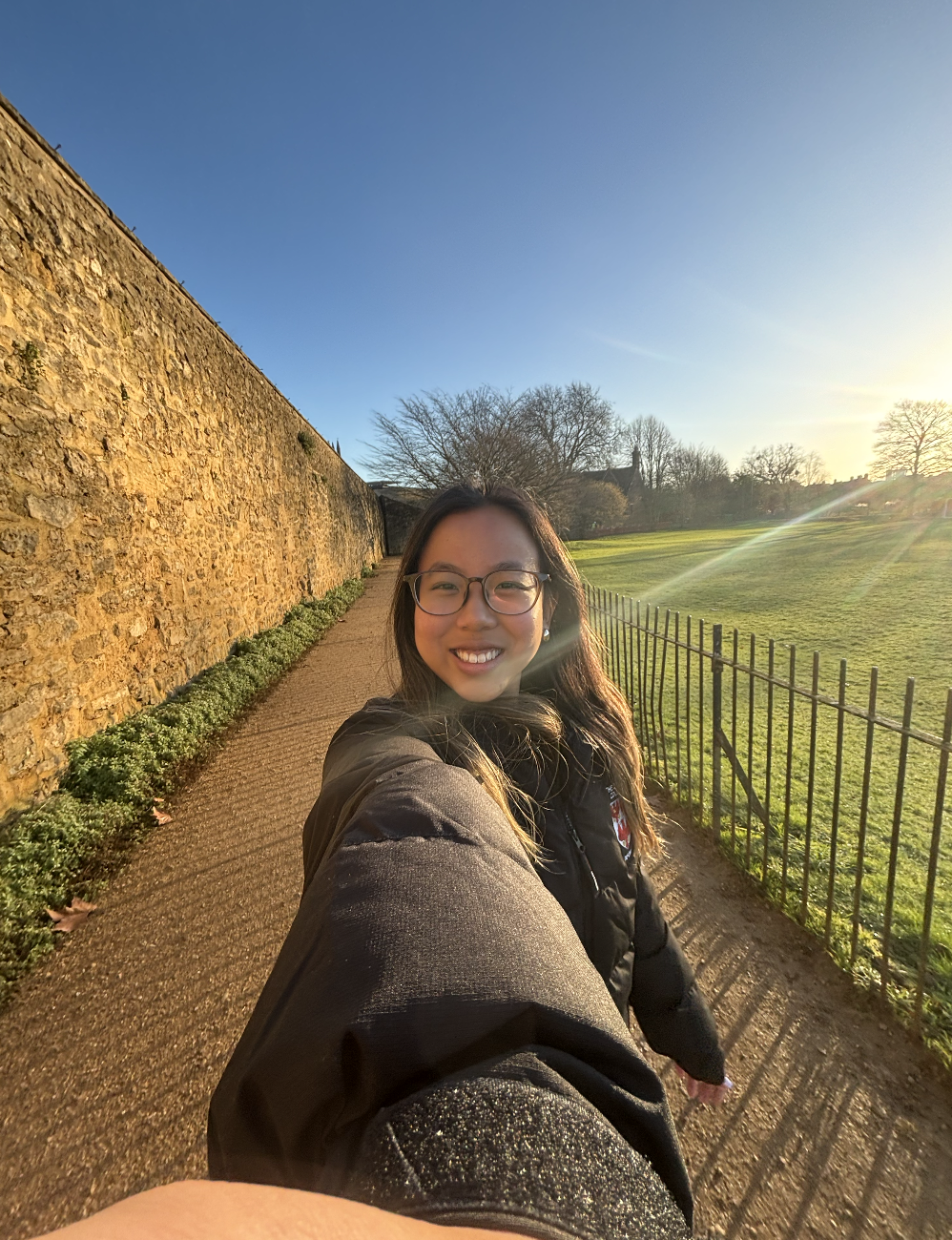 Ottillie profile photo. She holds the camera at arm's length and smiles. In the background is blue sky and sunshine.