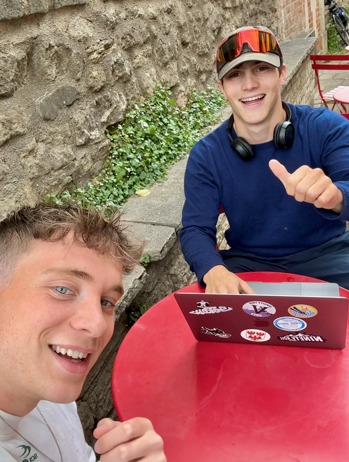 Harry and Jack sitting at a red table with a laptop and planning the running route