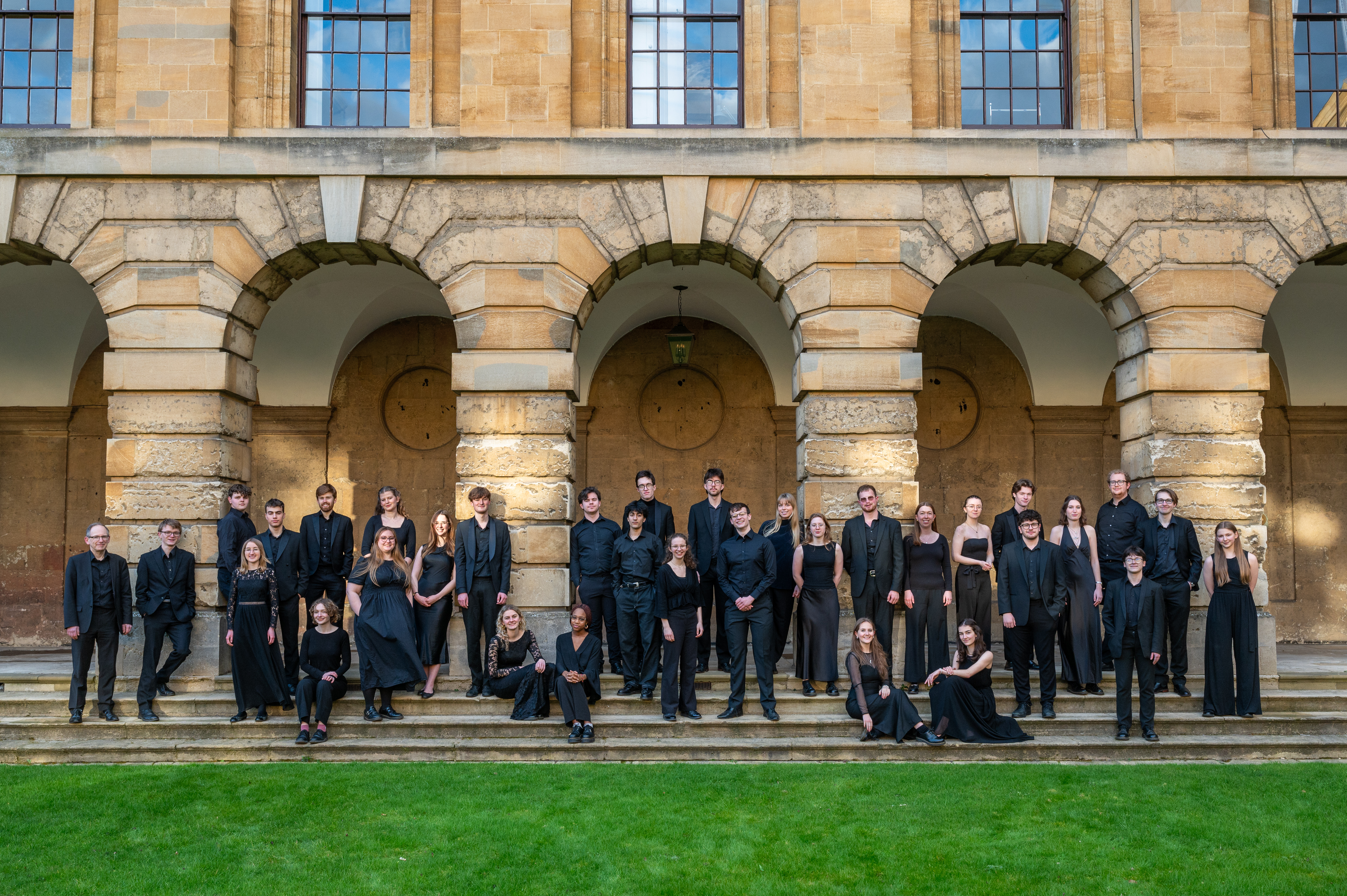 the choir dressed in black and standing in a group on the steps of Front Quad