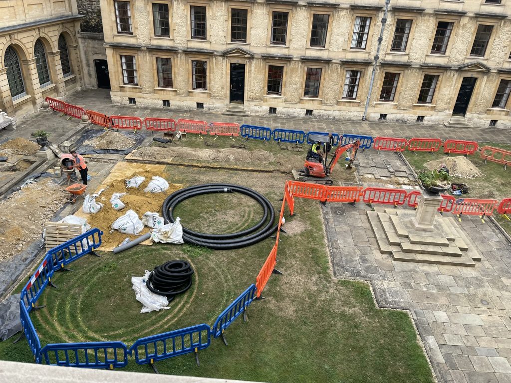 an aerial view of works in the Back Quad showing various sections dug up and piping laid across the lawn