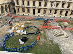 an aerial view of works in the Back Quad showing various sections dug up and piping laid across the lawn