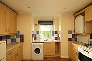 Example kitchen at Venneit Close showing a window, kitchen cabinets and washing machine