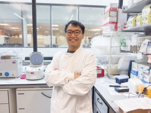 Peter Wan pictured standing in his laboratory wearing a white lab coat