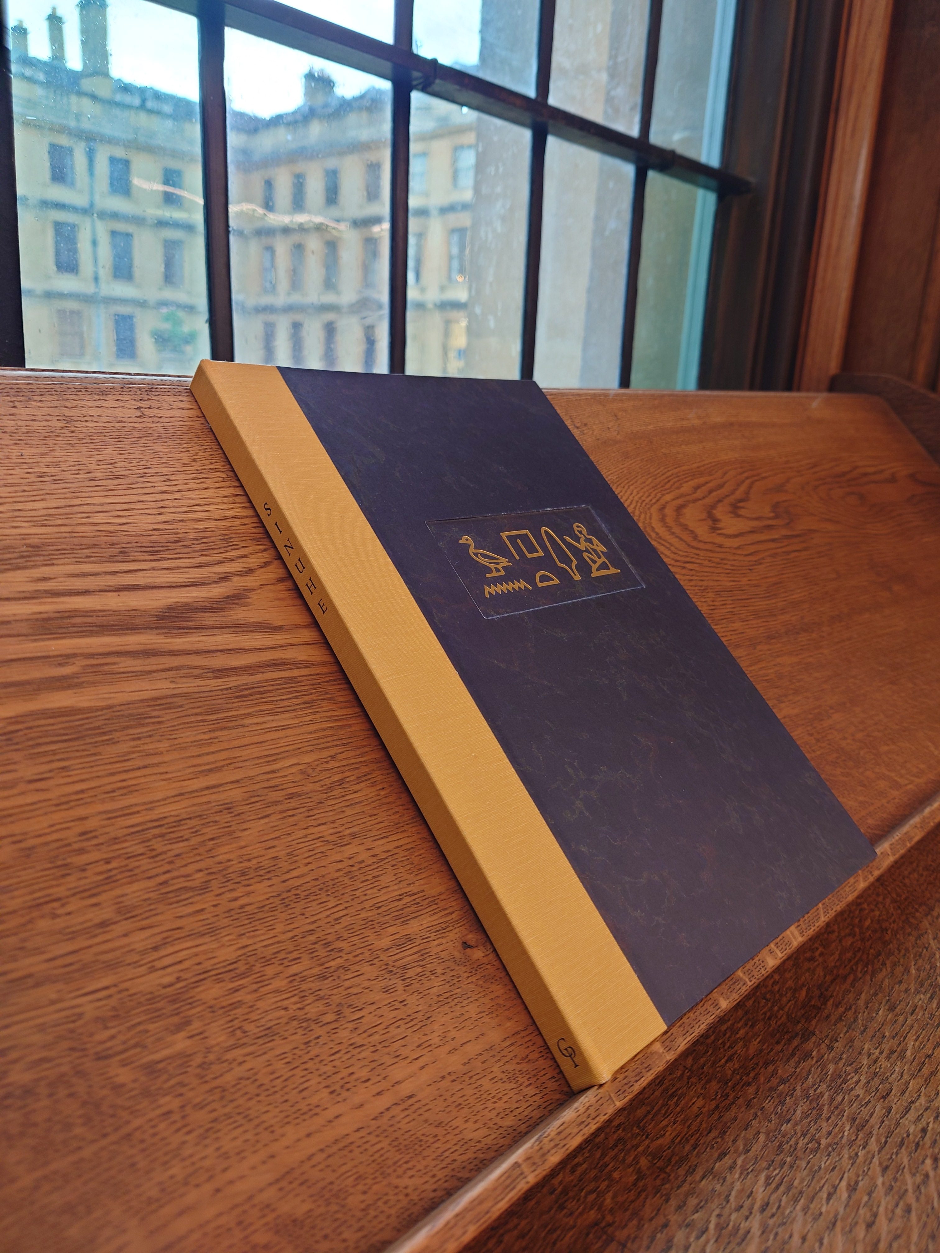 The Sinuhe book closed and sitting on a shelf by a window