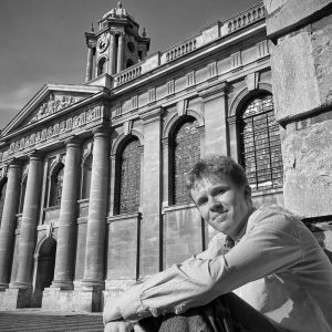 Danny McAlea sitting in Front Quad with the clock tower in the background