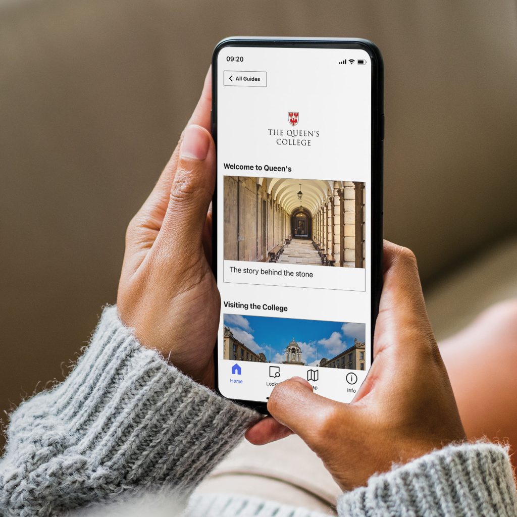 a photo showing hands holding a mobile telephone; on the screen is the homescreen for the College's guide on Bloomberg Connects