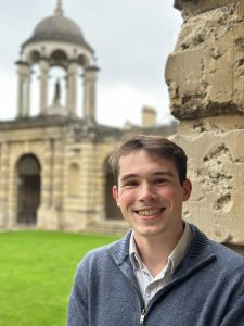 Profile photo of Dan Kelly who stands smiling in Front Quad with the cupola in the background