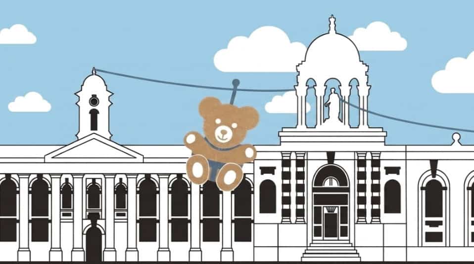 Cartoon image of Teddy Bear ziplining in front of Queen's FQ buildings