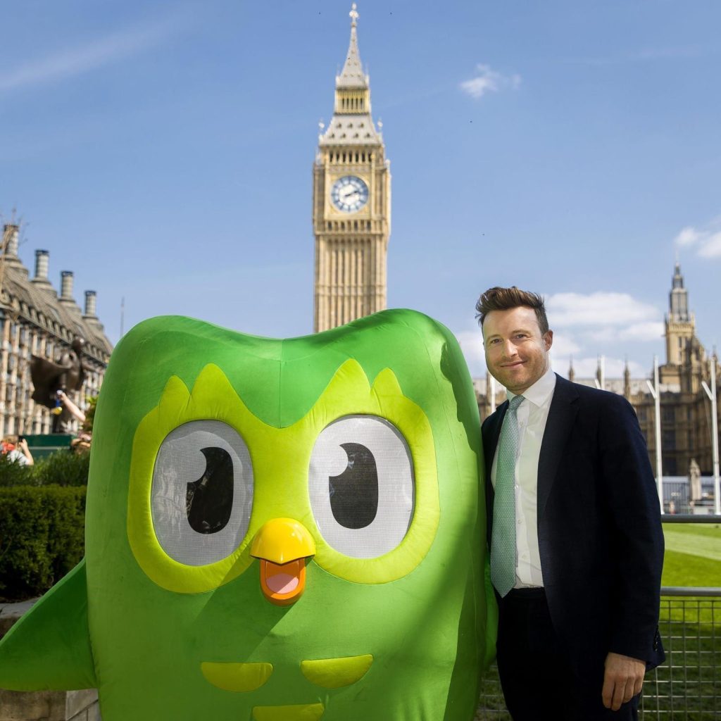 Michael Lynas standing with the green owl from DuoLingo outside the Houses of Parliament