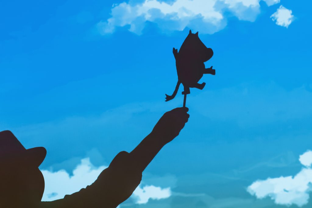 Puppet theater silhouettes of Moomin trolls. Doll in hand behind the curtain. Silhouette Mumiy Troll keeps actor puppeteer