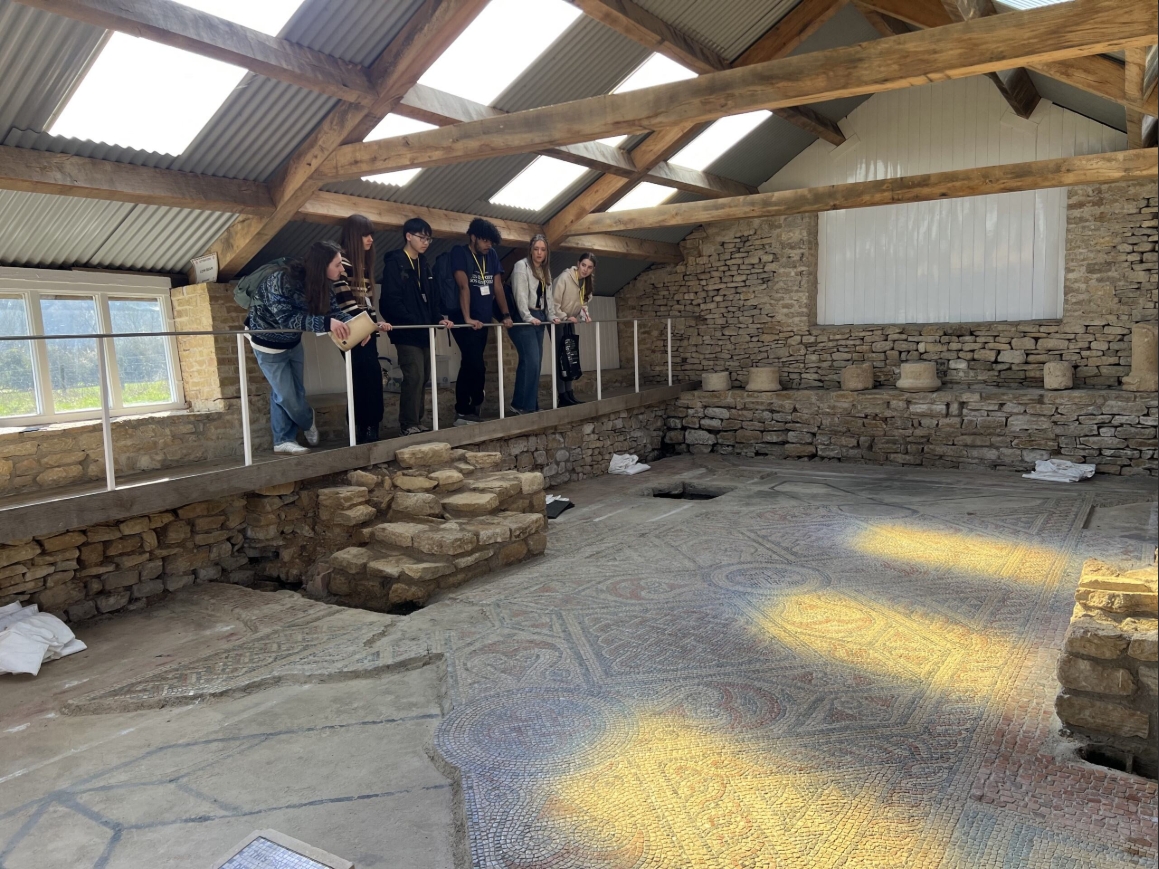 a school group examining the mosaic floor at North Leigh Roman Villa