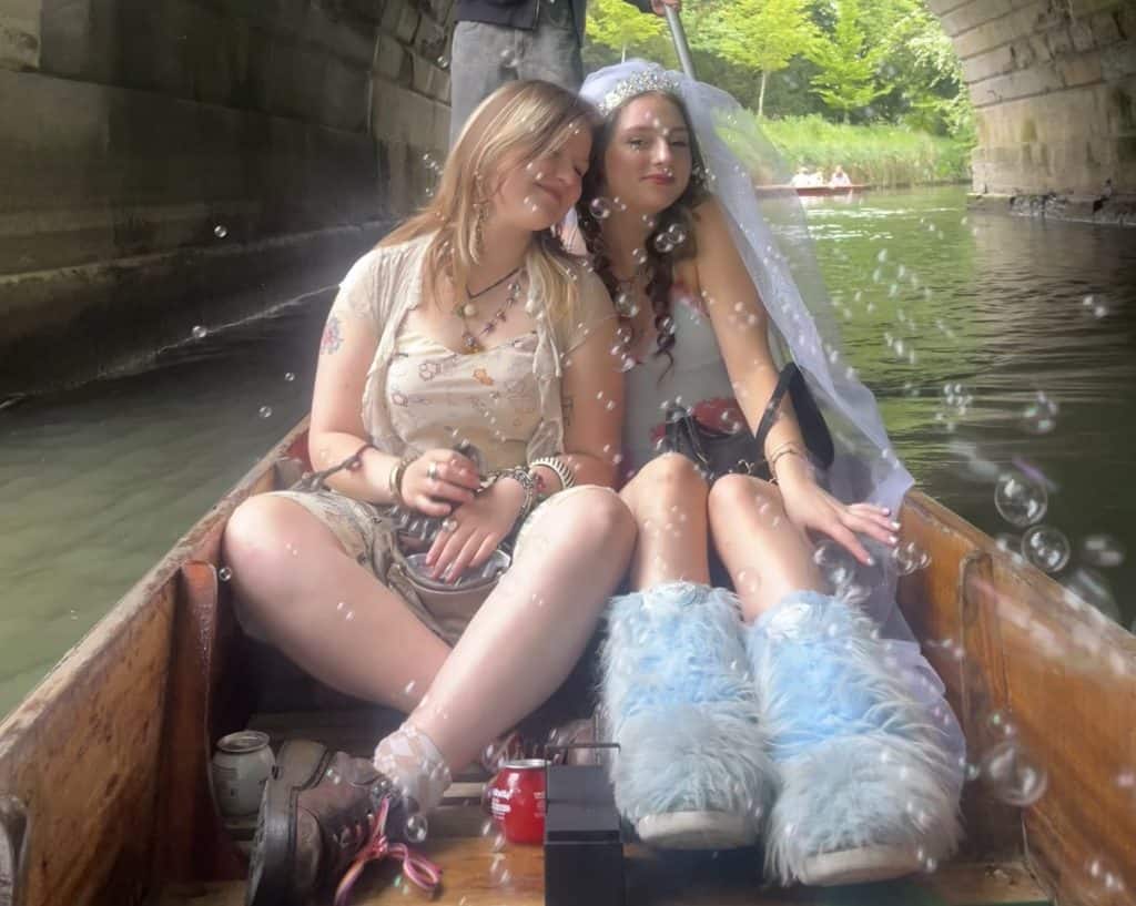 Rosa and Maia pictured together sitting in a punt on the river with bubbles floating in front of them