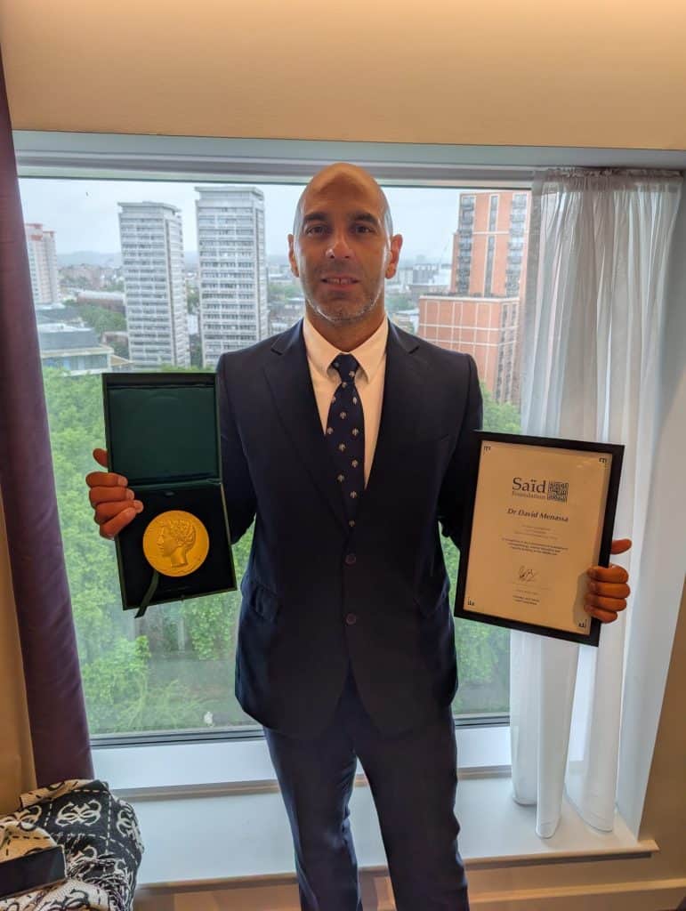 David Menassa pictured holding the Alumni Achievement Award.