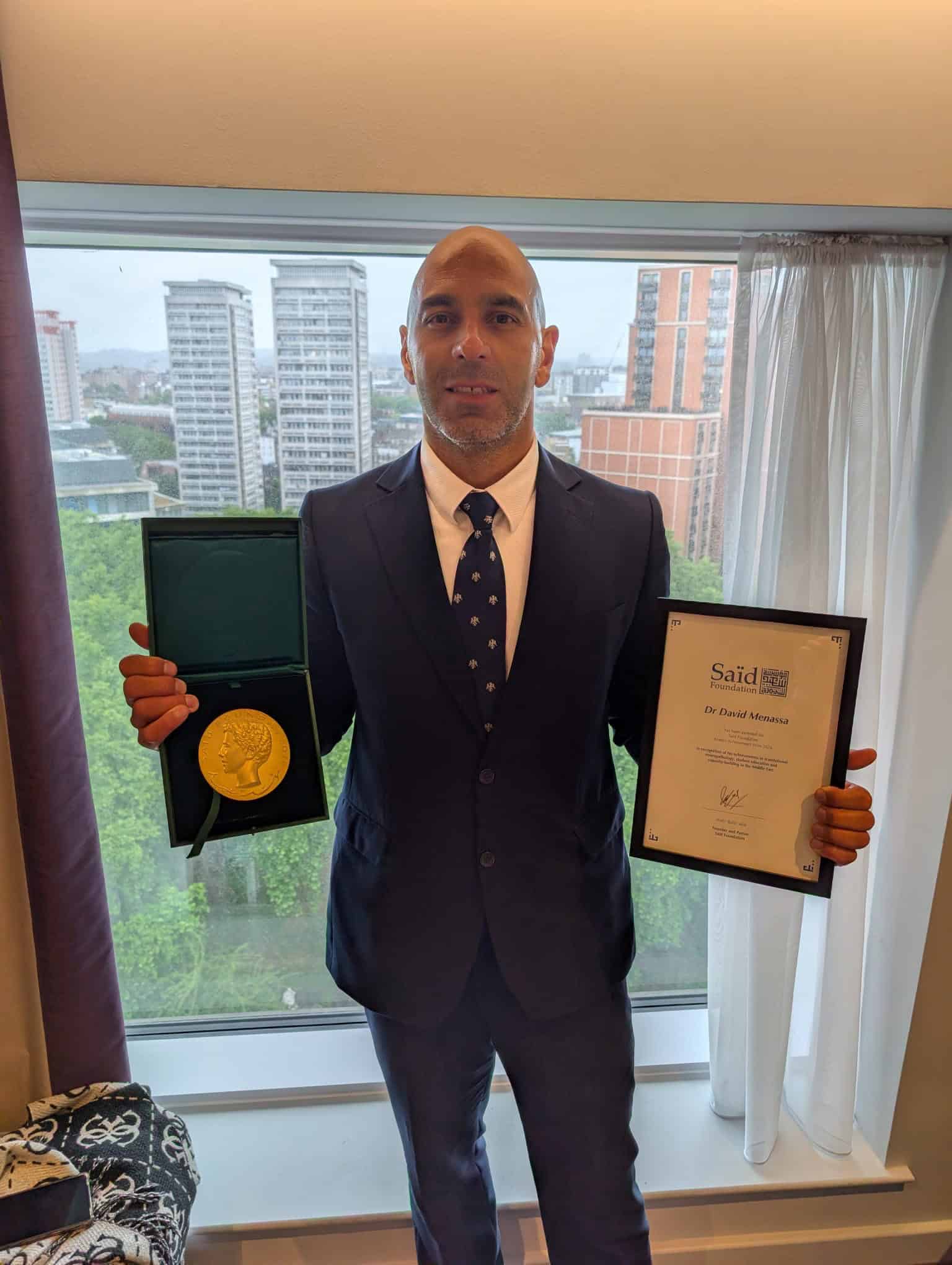 David Menassa pictured holding the Alumni Achievement Award.