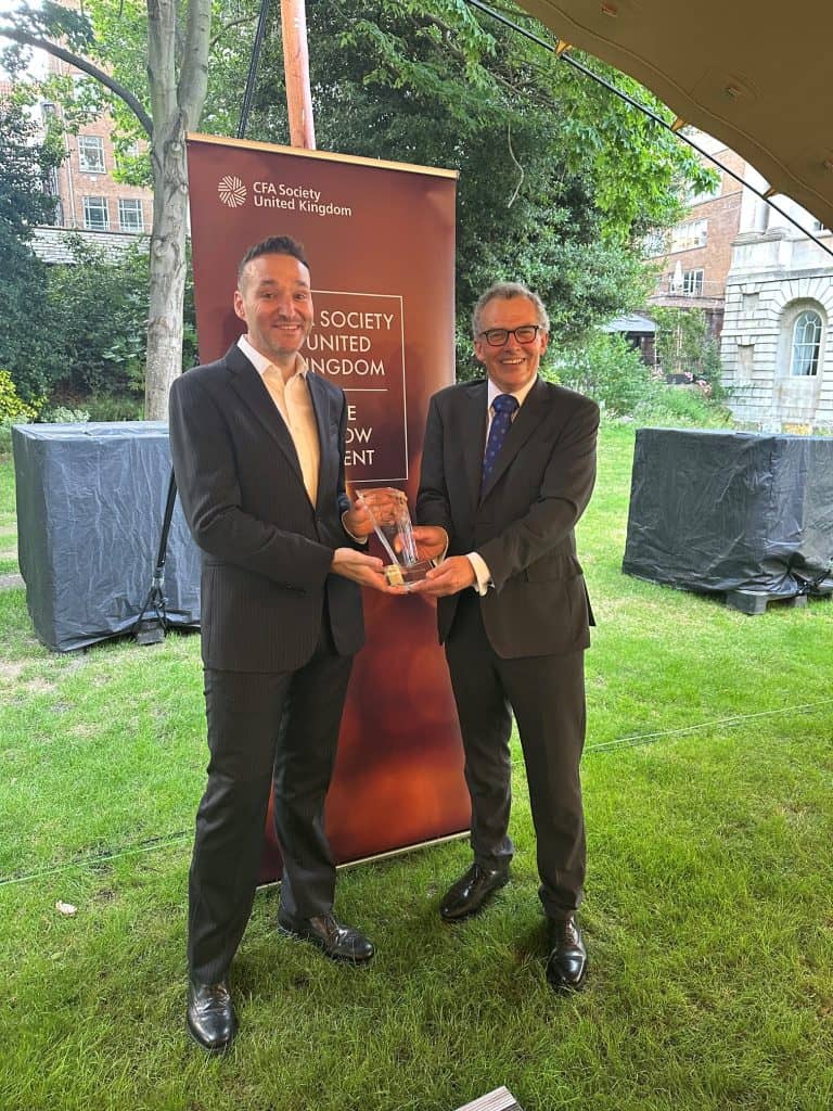 Ludo Phalippou pictured receiving an award- he is standing on grass receiving the award and standing in front of a banner