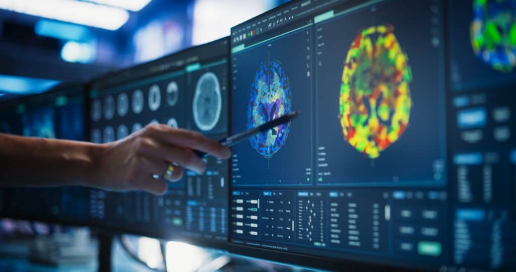 Modern Medical Research Center: Anonymous Doctor Pointing At Desktop Computer Monitor With CT Scan Of Patient's Spinal Cord. Specialist Looking For Tumors Or Damage, Looking For Treatment Methods.