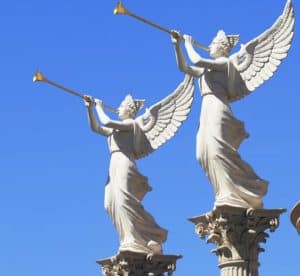Blue sky background with angel statues blowing golden horns